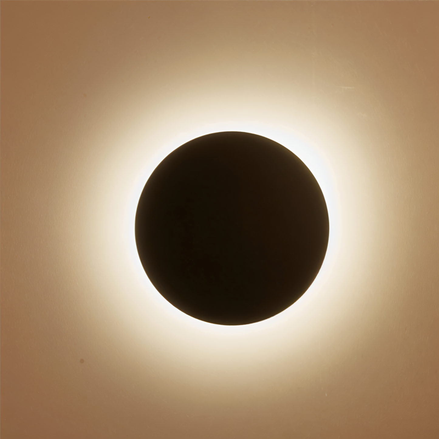 Solar eclipse with a dark circular shadow on a light brown background