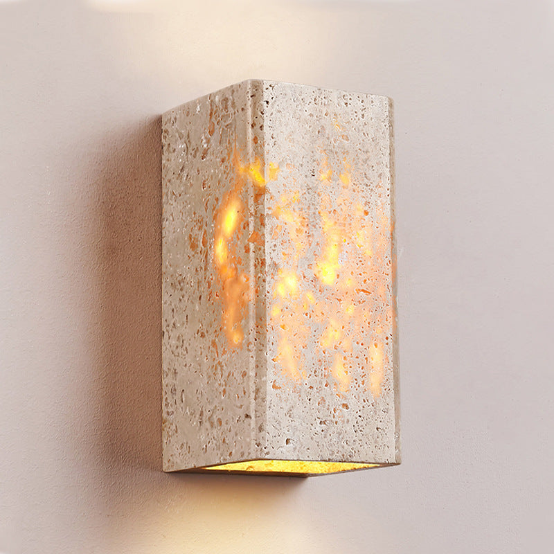 Concrete wall sconce with a warm glow on a neutral background