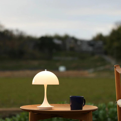 Table lamp and mug on a wooden table with a blurred natural background