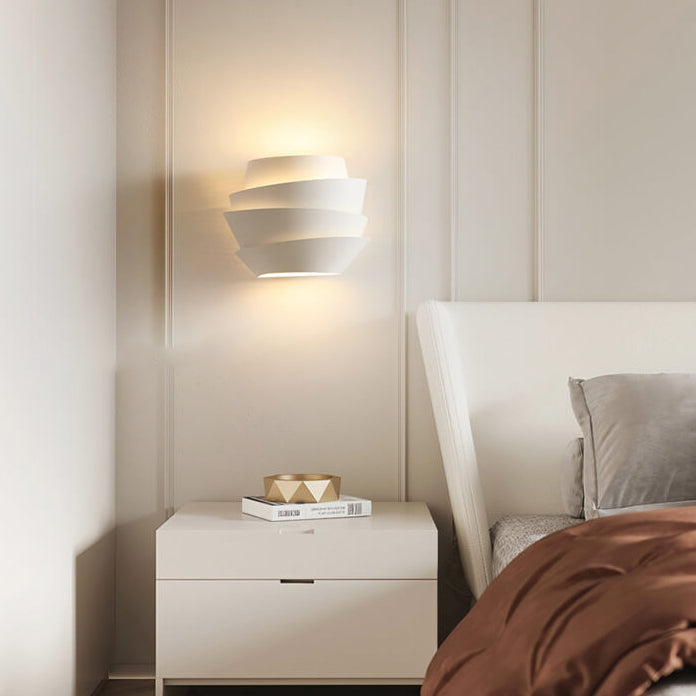 Modern bedroom with a nightstand, wall lamp, and bed.