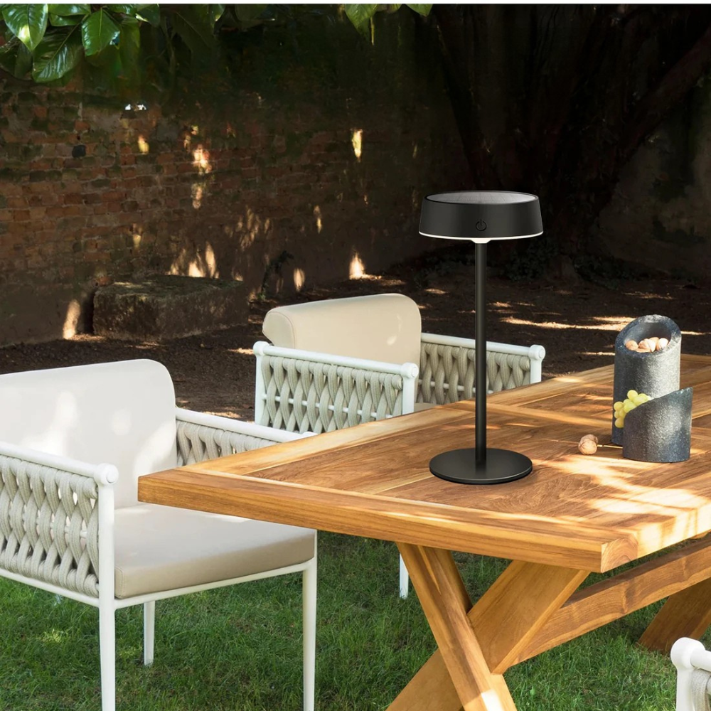Outdoor setting with wooden table, chairs, and a black lamp.