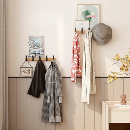 Wall-mounted coat rack with clothes and a hat in a room setting