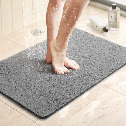 Person stepping onto a gray bath mat in a bathroom setting.