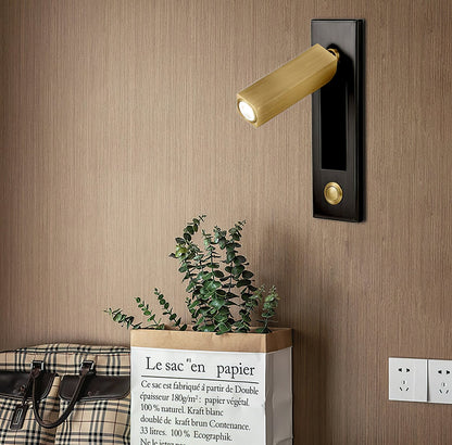 Decorative wall light fixture on a wooden wall with a plant and suitcase in the foreground.