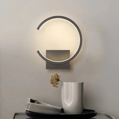 Modern wall lamp with a decorative vase and plant on a table below.