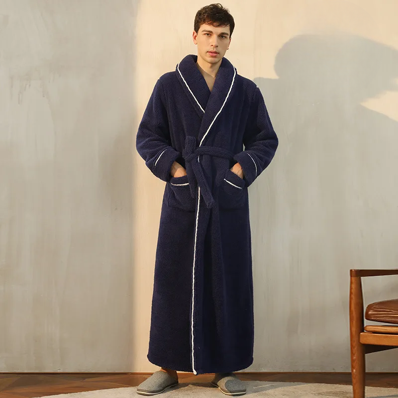 Man wearing a navy blue robe with white trim in a room with wooden floor and chair.