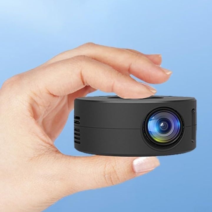 Small black camera held in a hand against a blue background