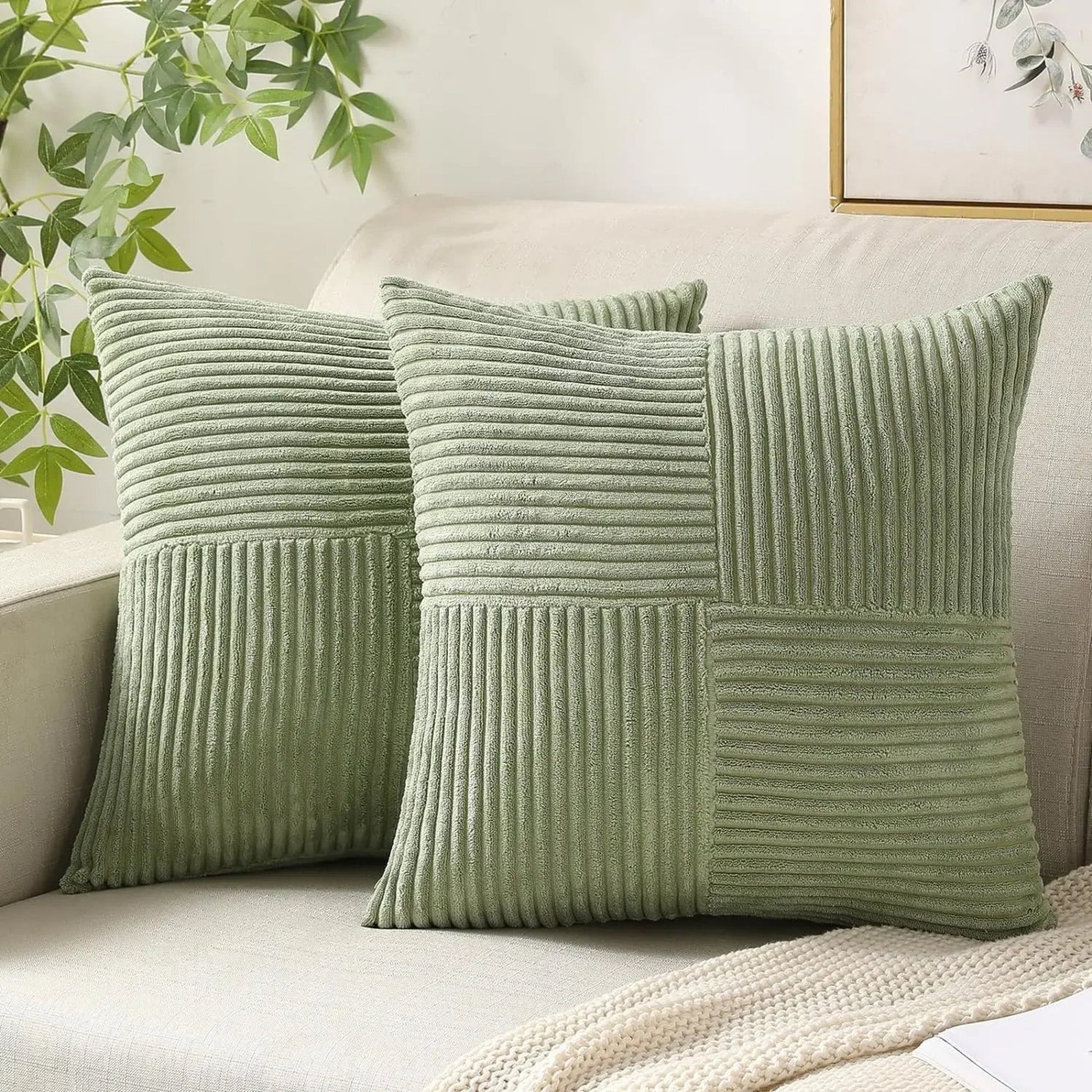Two green textured pillows on a sofa with a plant and framed picture in the background.