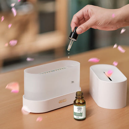 Hand using a dropper to add liquid into a white electronic device on a wooden surface with a bottle in the foreground.