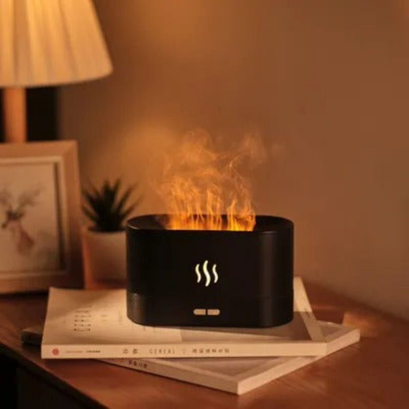 Black fire pit with flames on a wooden surface, surrounded by books and decor items.