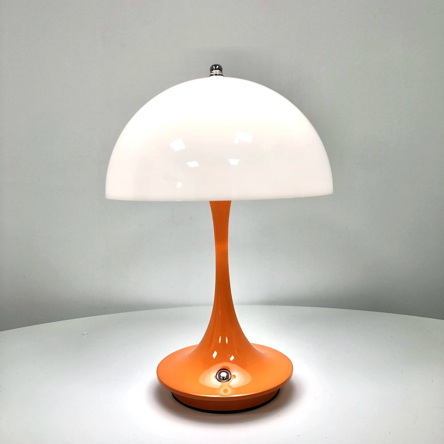 Table lamp with white shade and orange base on a gray background