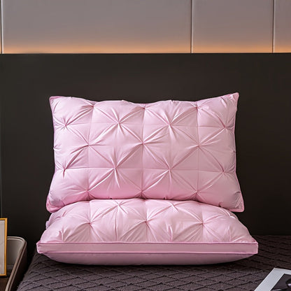 Two pink quilted pillows on a bed with a dark headboard.