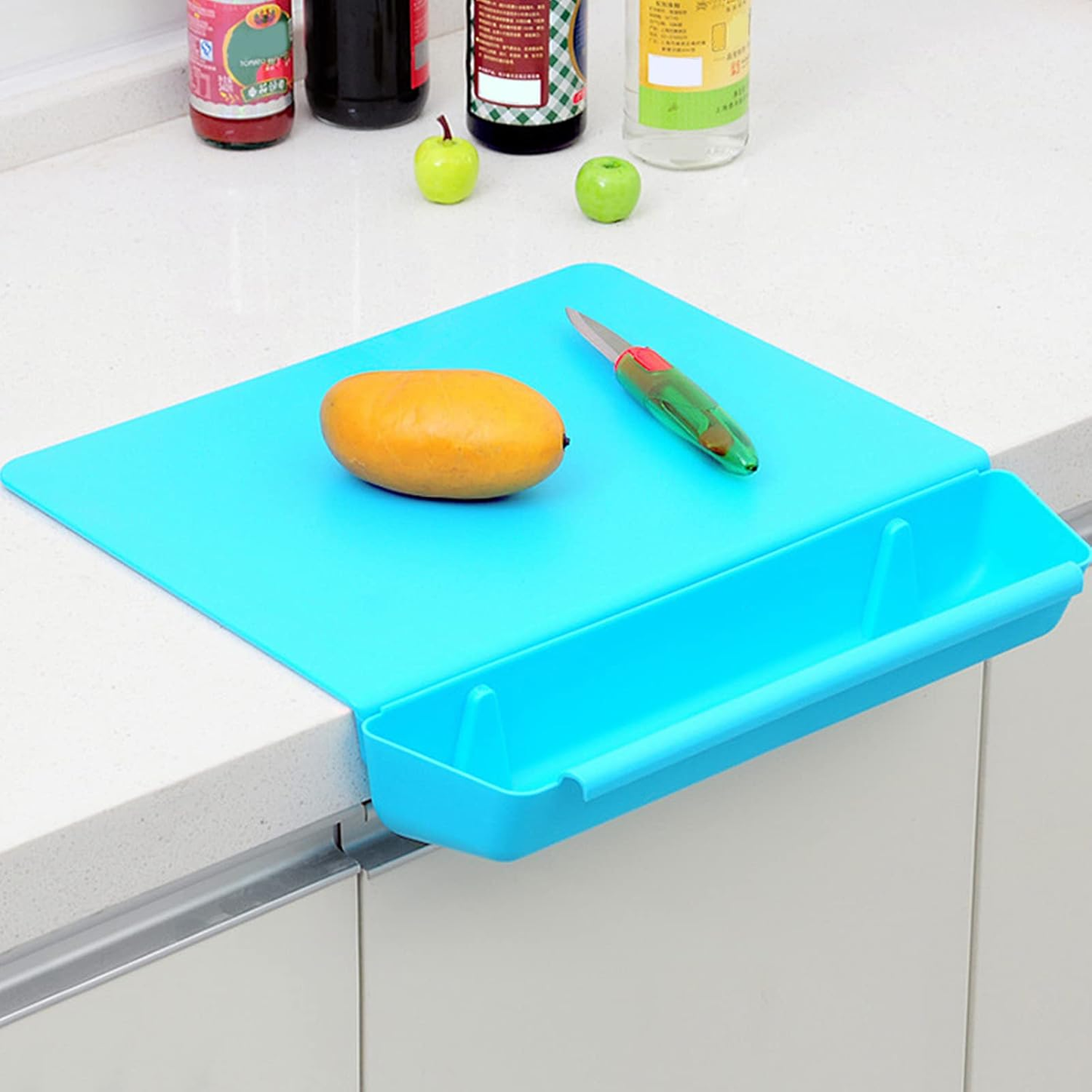 Blue cutting board with a mango and knife on a kitchen counter.
