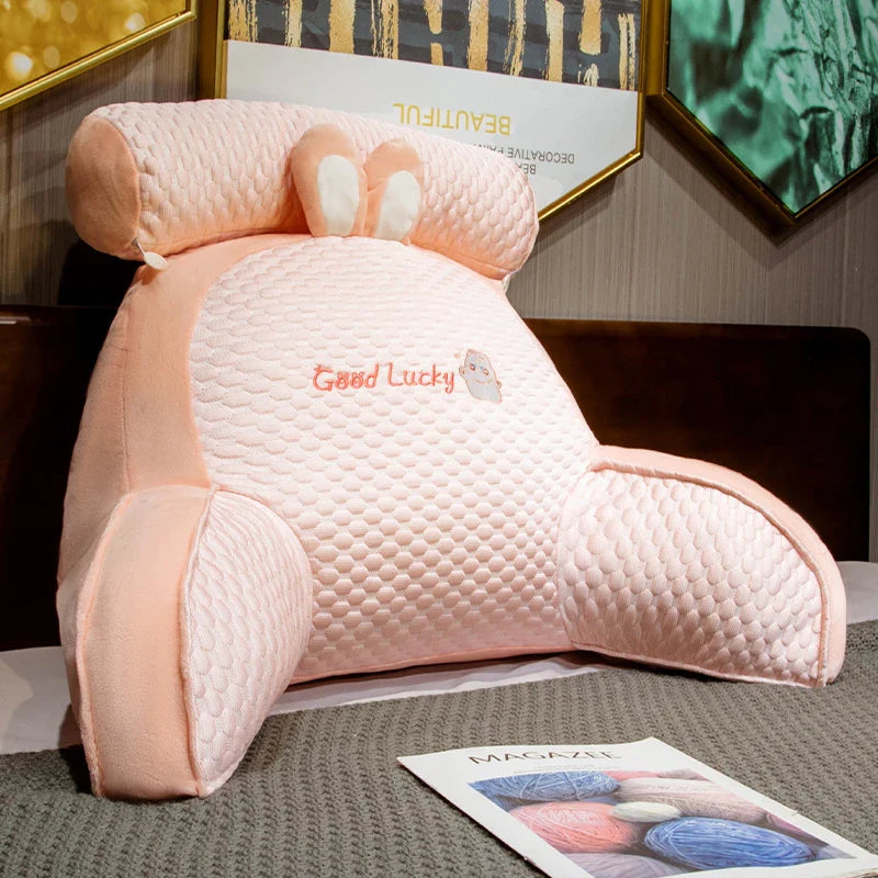 Pink plush toy with 'Good Lucky' text on a surface with a magazine underneath.