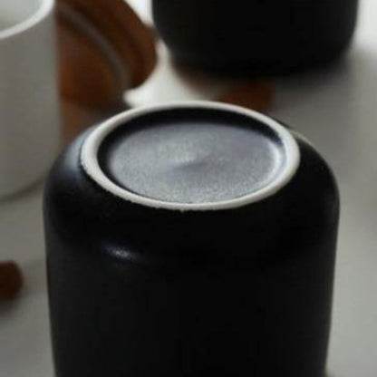 Close-up of a black ceramic container with a lid on a light background
