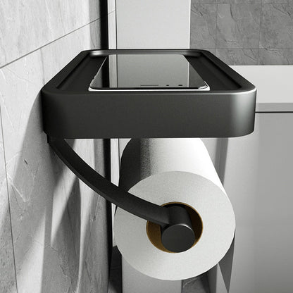 Black wall-mounted toilet paper holder with a roll of toilet paper on a tiled bathroom wall.